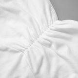 Close-up of the pleated detail on a white lace strap camisole tank top showcasing its soft knitted fabric.