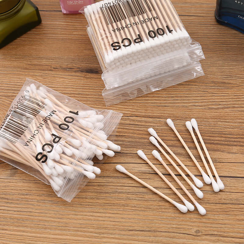 100pcs bag of baby cotton swabs on a wooden surface, showcasing the cotton ends and wooden sticks.