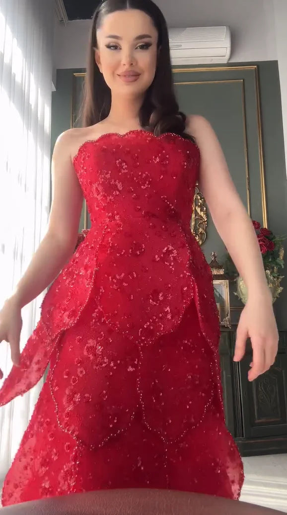 Beautiful woman in a stunning red beaded engagement gown with a tiered skirt, showcasing a strapless neckline.