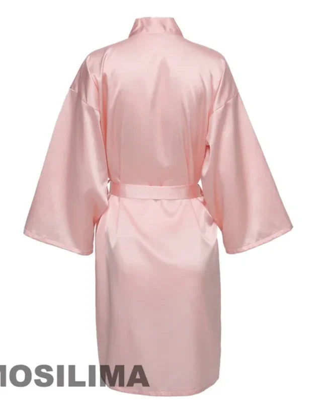 Back view of a knee-length pink satin kimono robe with wide sleeves and a tie belt.