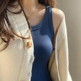 Woman wearing a blue padded cotton spaghetti camisole under a cream cardigan, showcasing a summer slim fit style.