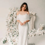 Bridal model wearing VG73 sheer wedding jacket over lace wedding dress, surrounded by white floral decor.