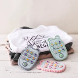Soft baby remote controls in pastel colors beside cute baby clothes, designed for early development and play.