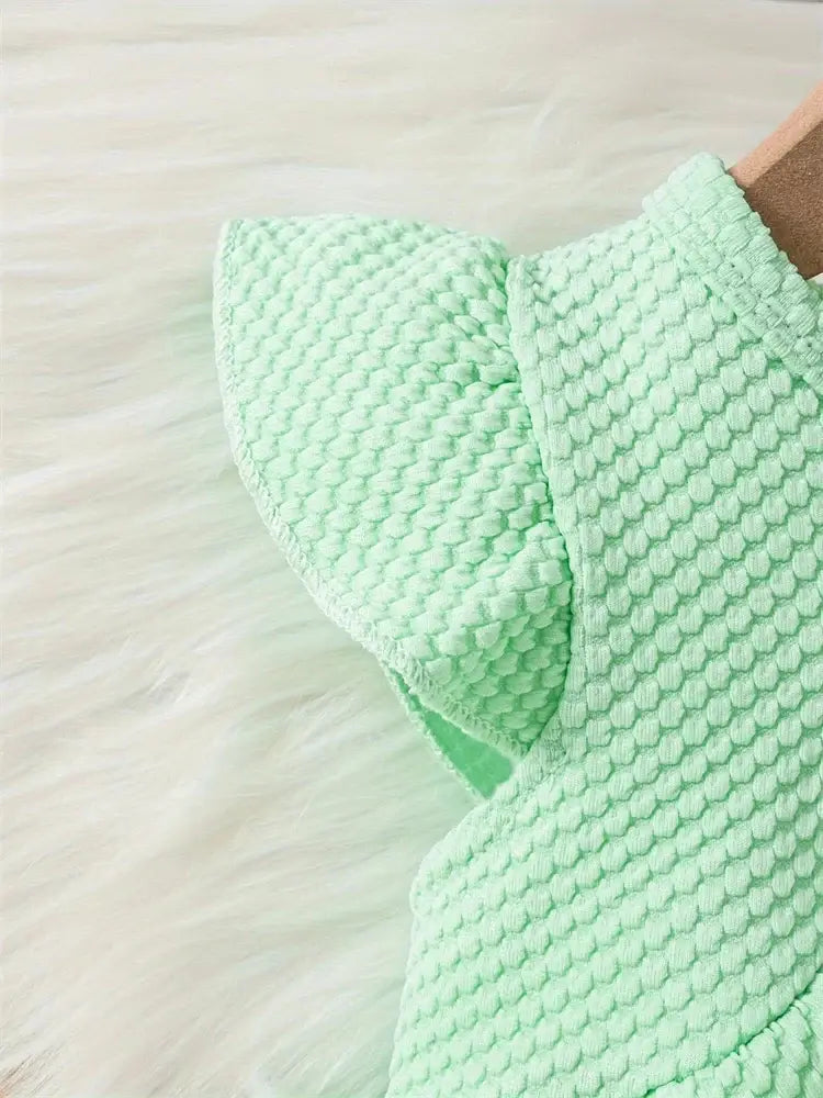 Mint green baby girls dress detail with textured fabric and ruffled sleeves, perfect for summer outings.