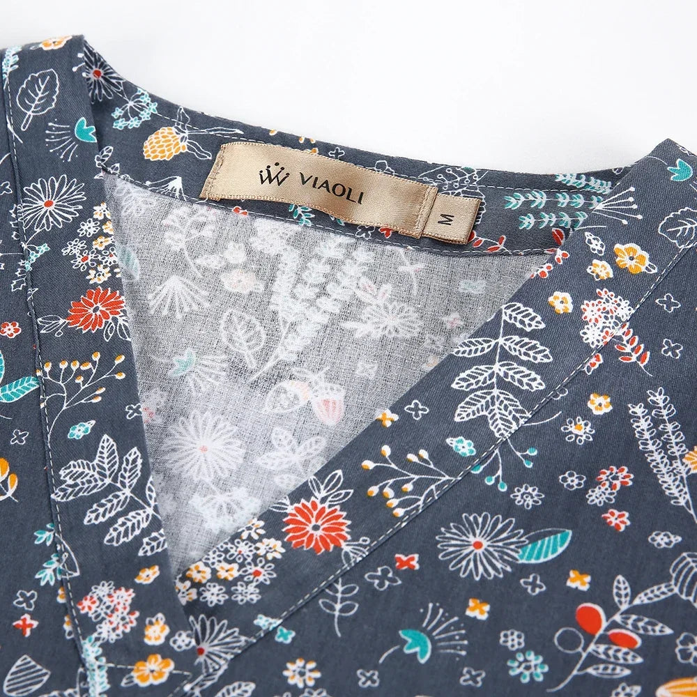 Close-up of a women's medical scrub top featuring colorful floral patterns and the VIAOLI brand tag.
