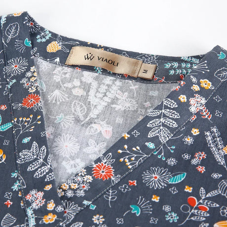 Close-up of a women's medical scrub top featuring colorful floral patterns and the VIAOLI brand tag.