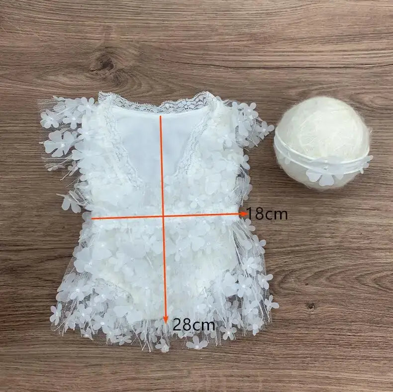 Newborn photography prop featuring a white floral romper and a soft ball, ideal for capturing sweet baby moments.