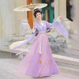 Elegant woman in a Hanfu traditional dress holding a parasol, showcasing a beautiful party outfit in a classic setting.