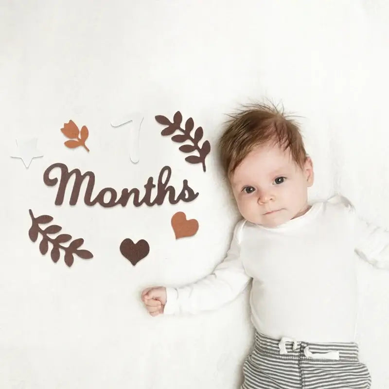 Baby milestone cards in soft felt displayed with baby at 7 months old on a cozy blanket.