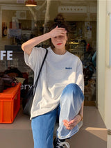 Oversized Harajuku streetwear tee in gray, worn casually with blue jeans, perfect for a relaxed day out.