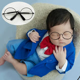 Newborn wearing colorful round glasses in a blue suit with red bow tie, perfect for photography accessories.