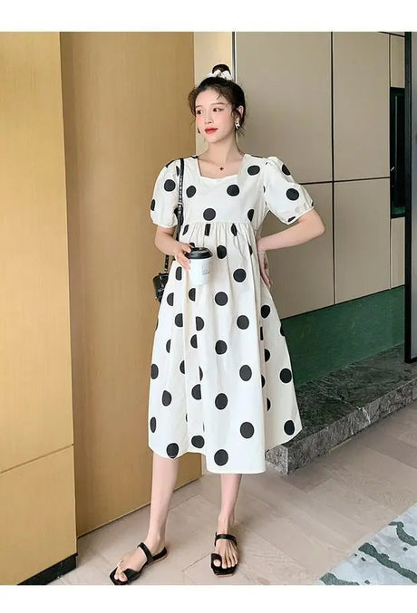 Polka dot loose maternity dress in white with black dots, perfect for summer, featuring short sleeves and a mid-calf length.