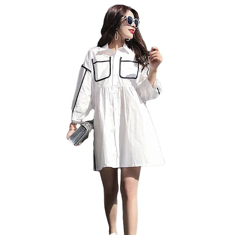 Model wearing a solid color white maternity shirt dress with pockets, perfect for summer beach parties.