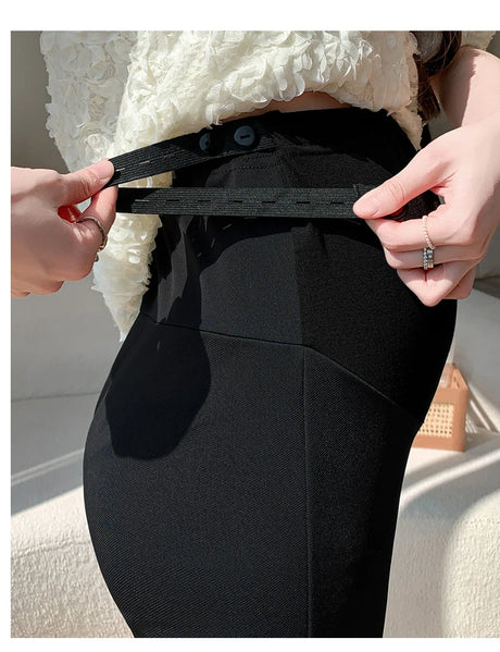 Woman adjusting the waistband of Y2K Bootcut Maternity Pants made of ice silk fabric.