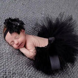 Adorable newborn girl in black tutu skirt and matching headband, perfect for baby photography and special occasions.