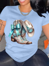 Elegant blue t-shirt featuring embellished cowboy boots design with turquoise accents, perfect for casual outfits.